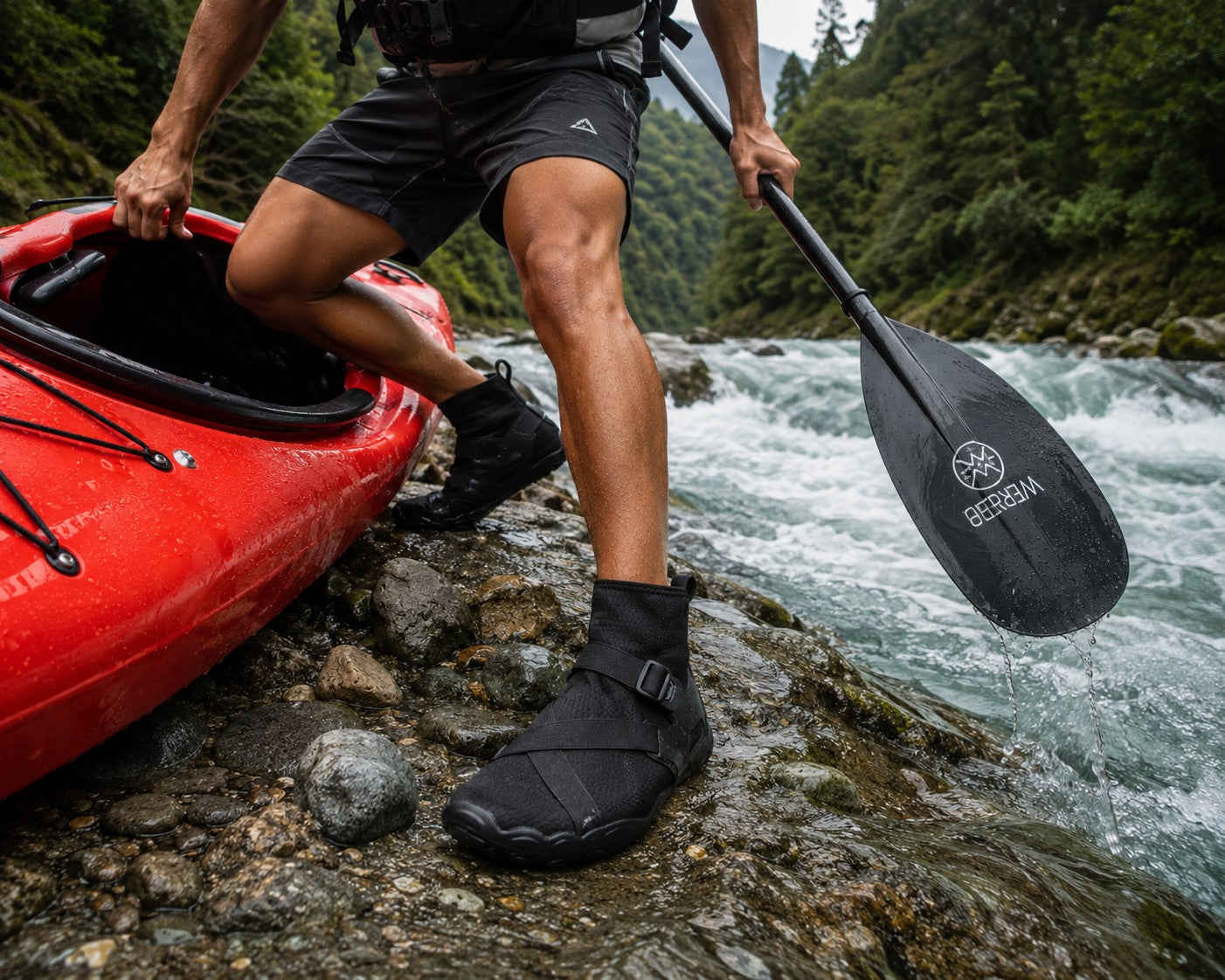Hombre usando botines acuáticos negros uzi sport guadalajara Wave Armor sobre rocas junto a un kayak rojo en un río