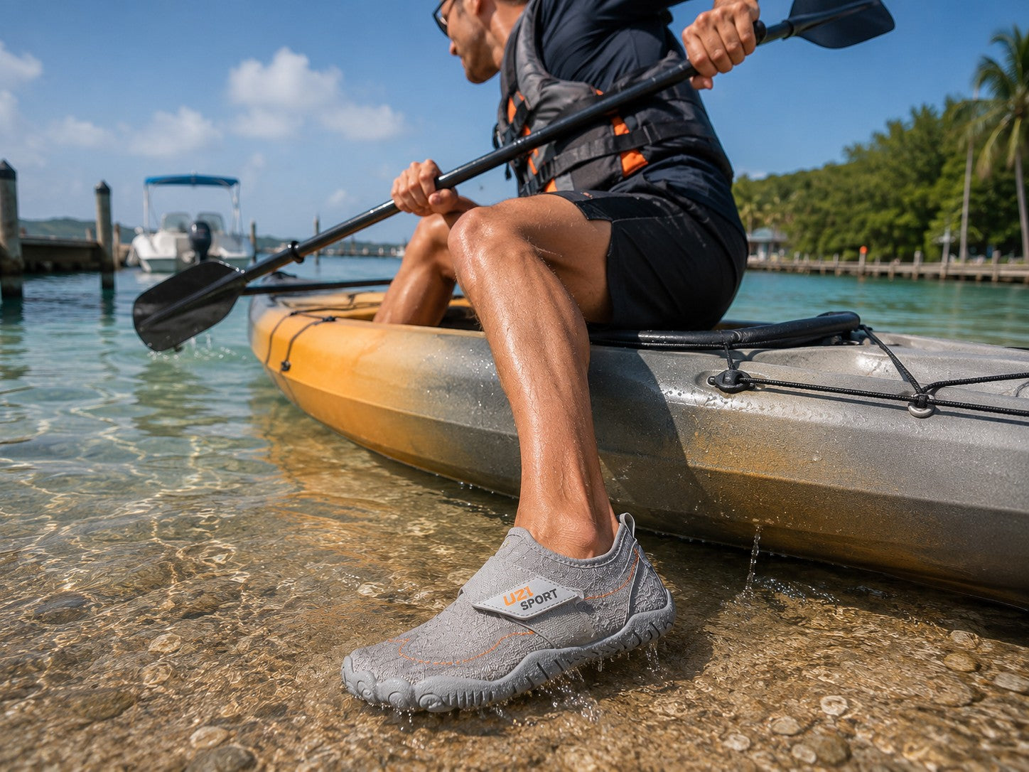 Hombre usando zapatos acuáticos uzi sport guadalajara Manta Flow grises mientras rema en un kayak en aguas poco profundas