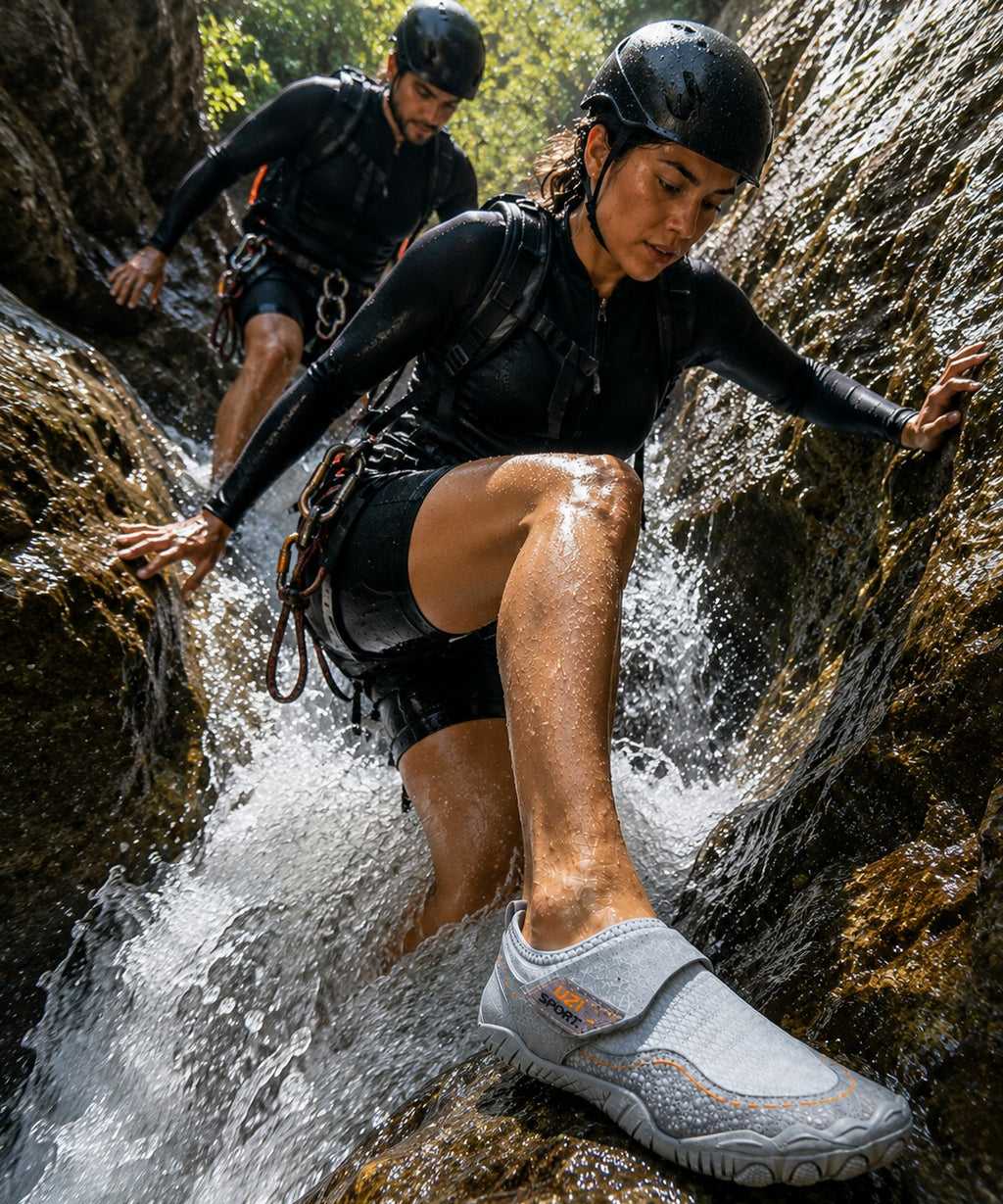 Mujer con zapato acuático uzi sport guadalajara gris cruzando un arroyo rocoso durante una aventura outdoor