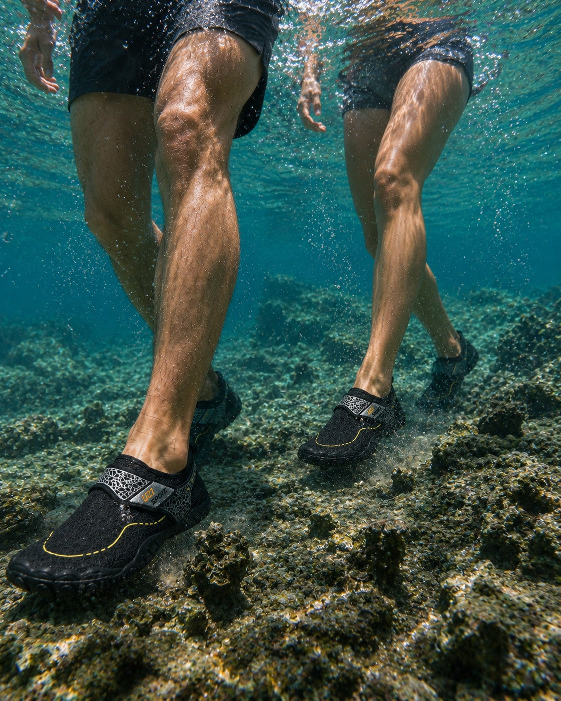 Personas caminando bajo el agua con zapatos acuáticos Manta Flow Black de uzi sport guadalajara sobre rocas marinas