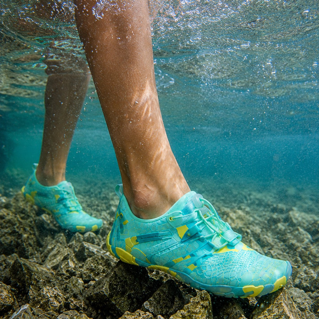 Zapato de playa uzi sport guadalajara Octopus Aqua turquesa con suela amarilla, sumergido bajo el agua sobre rocas.